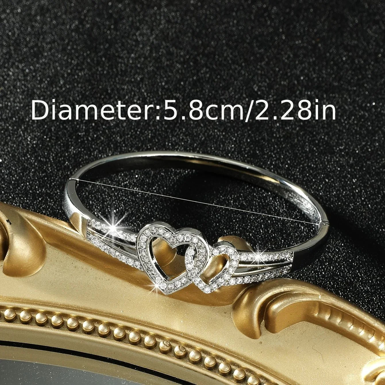 Silver bracelet with heart design on a gold surface, showing size measurement.