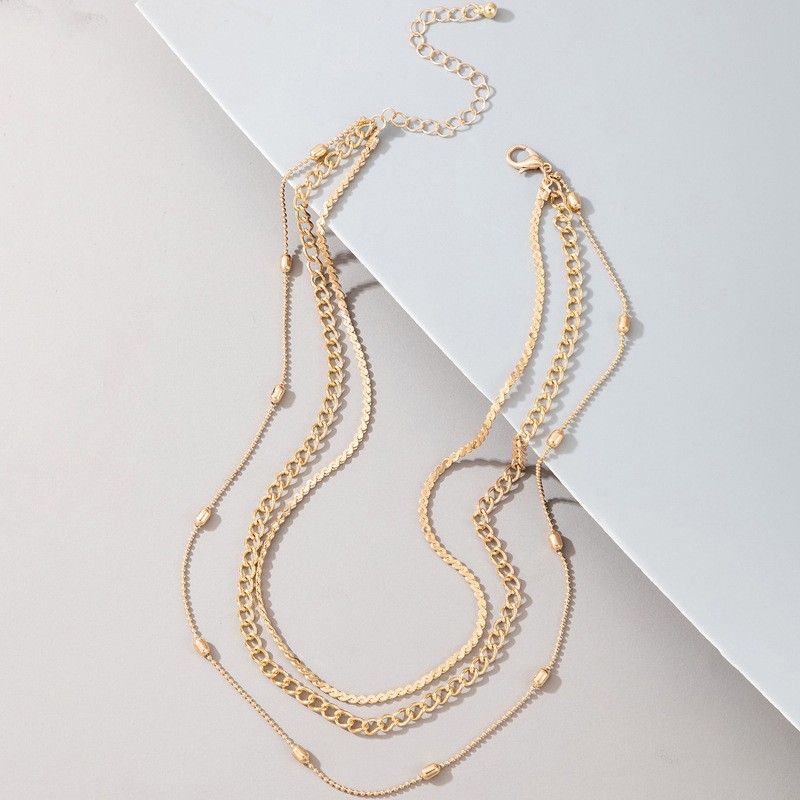 Set of gold chain necklaces on a light gray background