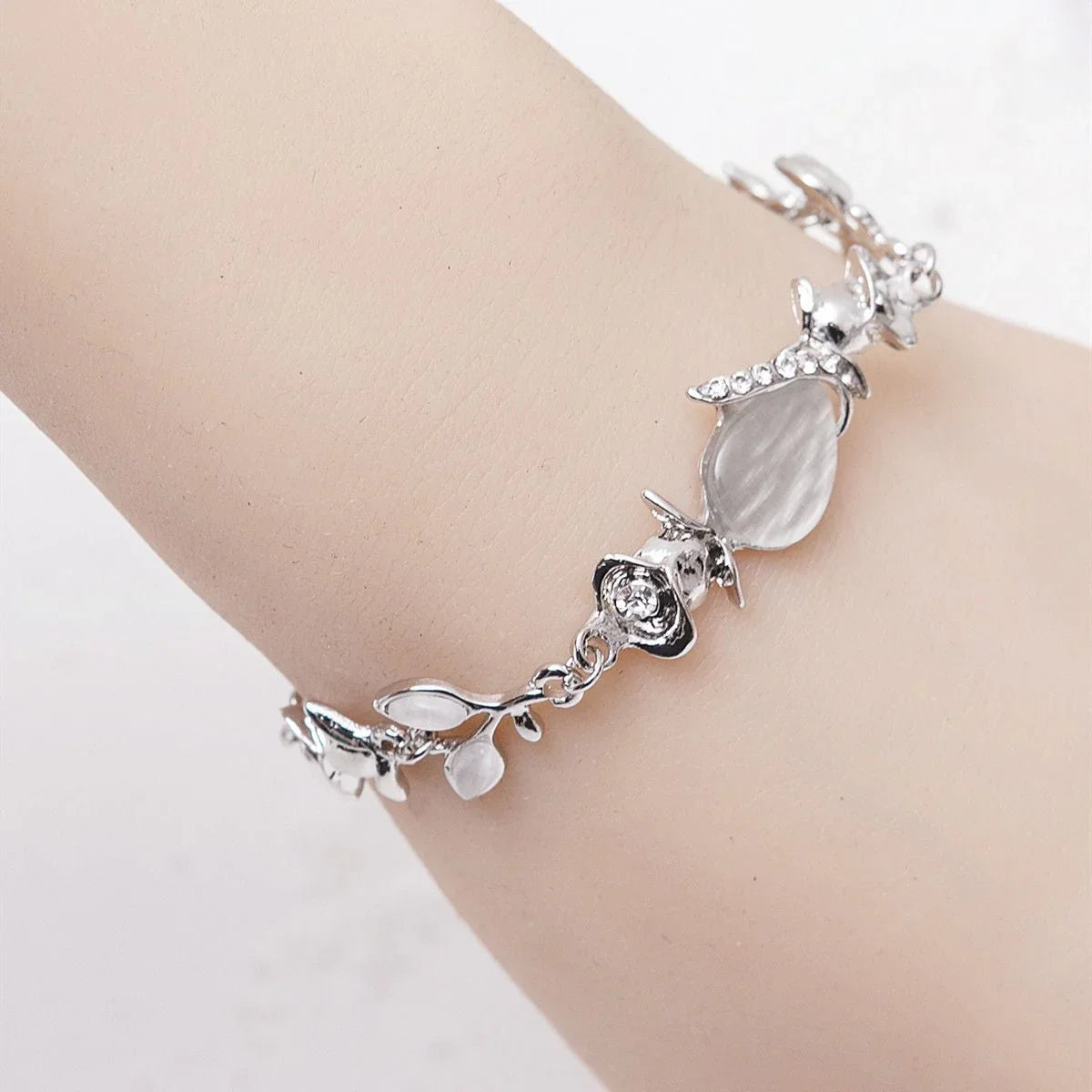 Silver bracelet with leaf designs on a wrist against a white background