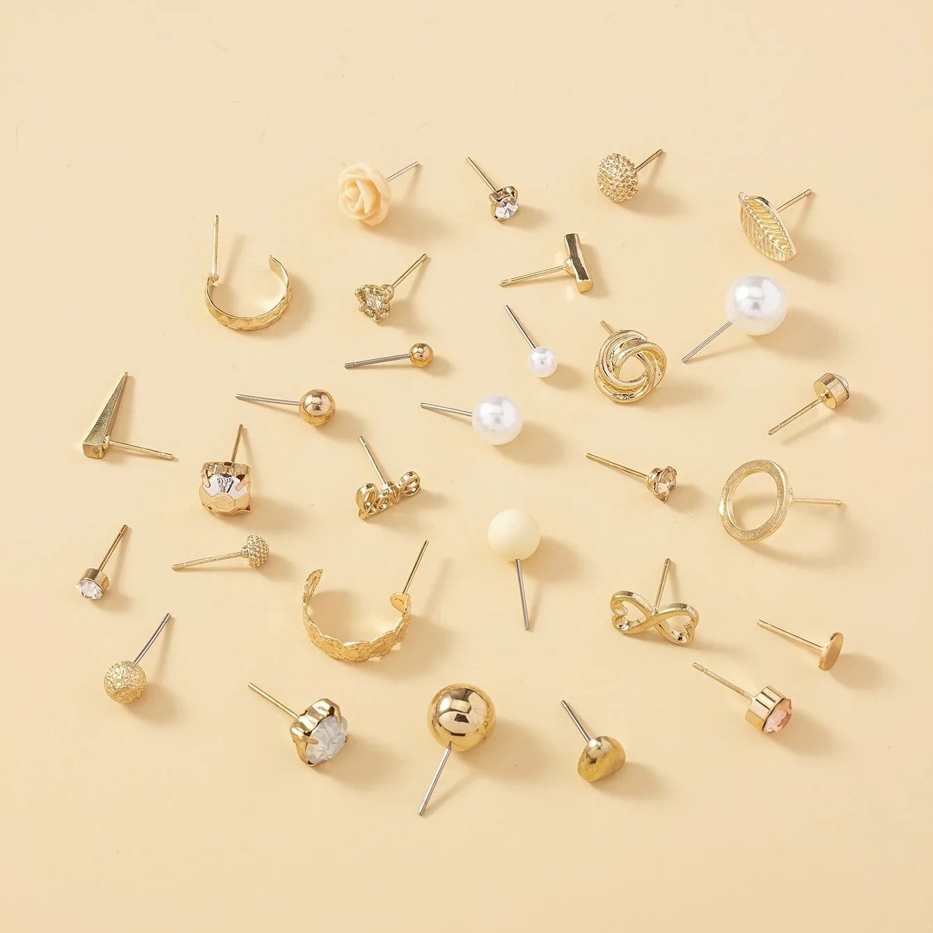 Various gold earrings on a beige background