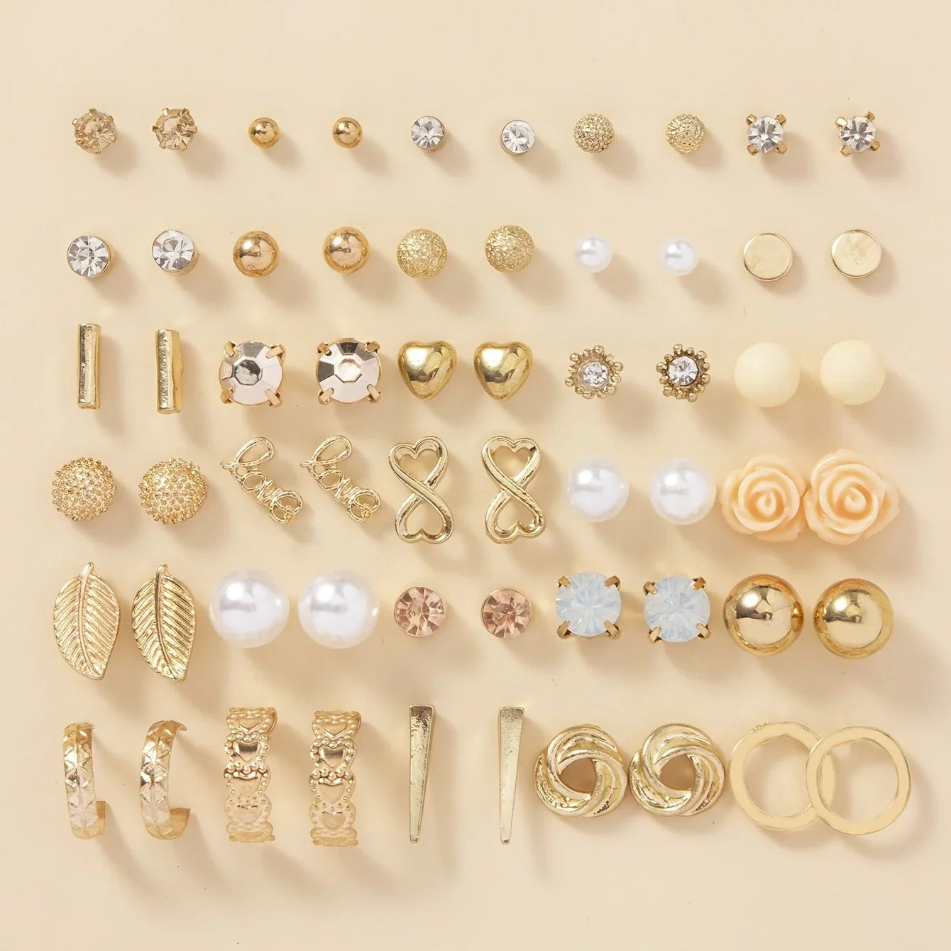 Collection of various gold and rose gold earrings on a beige background