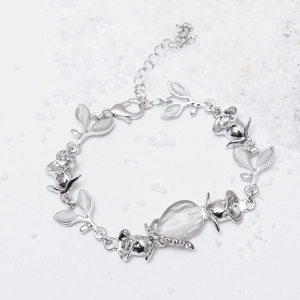 Silver bracelet with leaf and crystal charms on a light background
