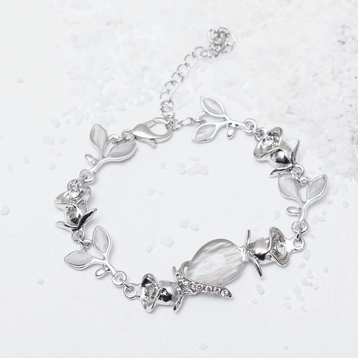 Silver bracelet with leaf and crystal charms on a light background