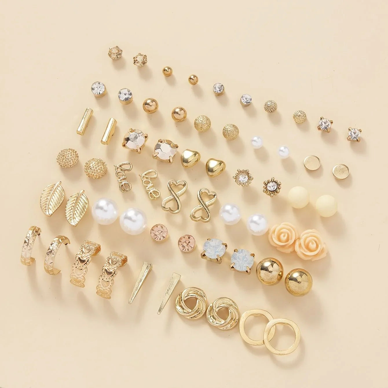 Assorted gold and pearl earrings on a beige background