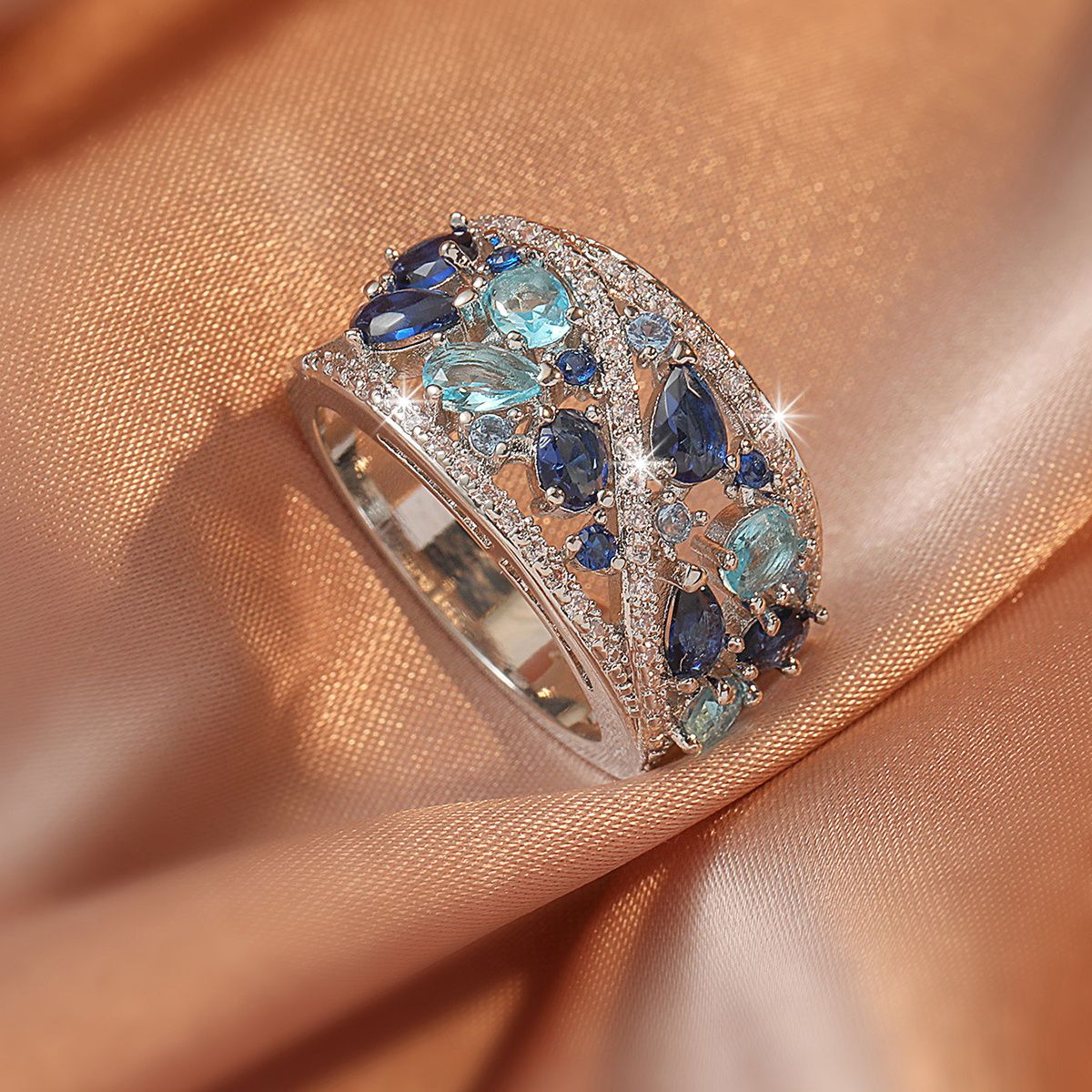 Elegant ring with blue gemstones on a peach fabric background