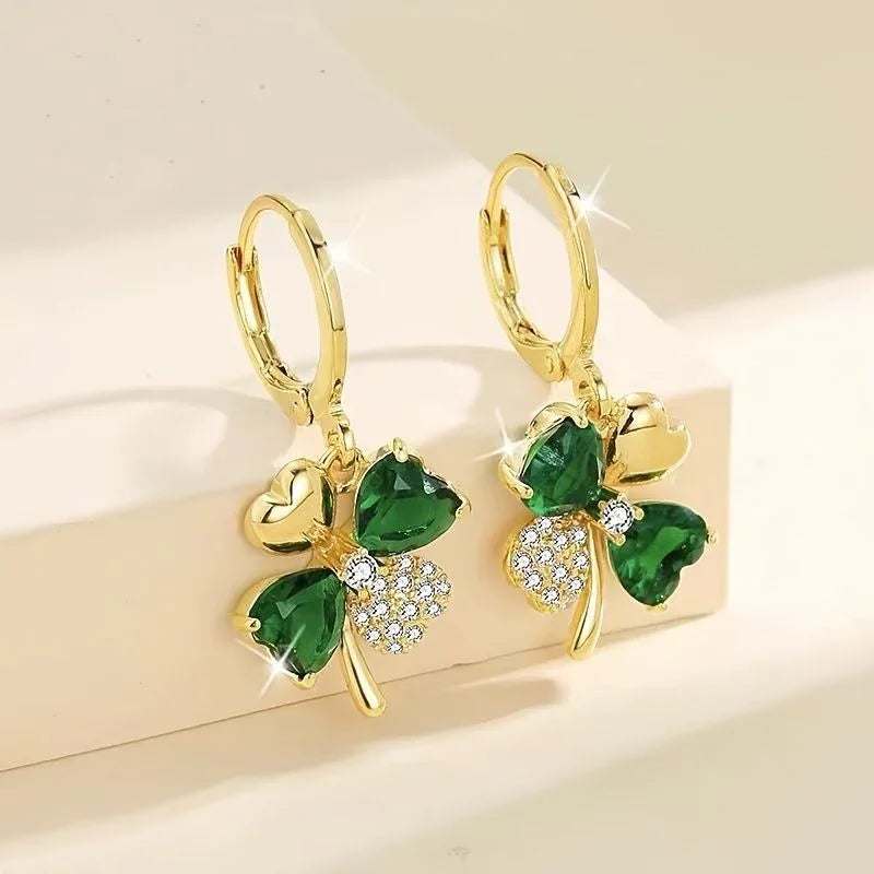 Gold earrings with green gemstones on a beige background
