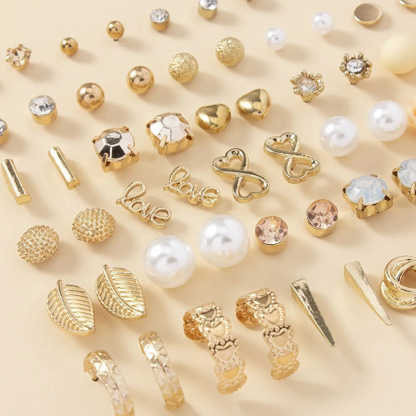 Assorted gold and pearl earrings on a beige background