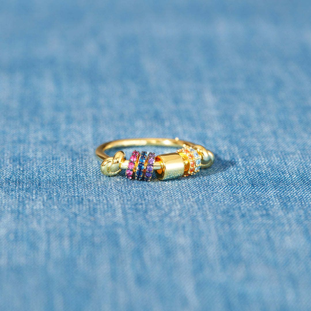 Gold ring with colorful beads on a blue denim background