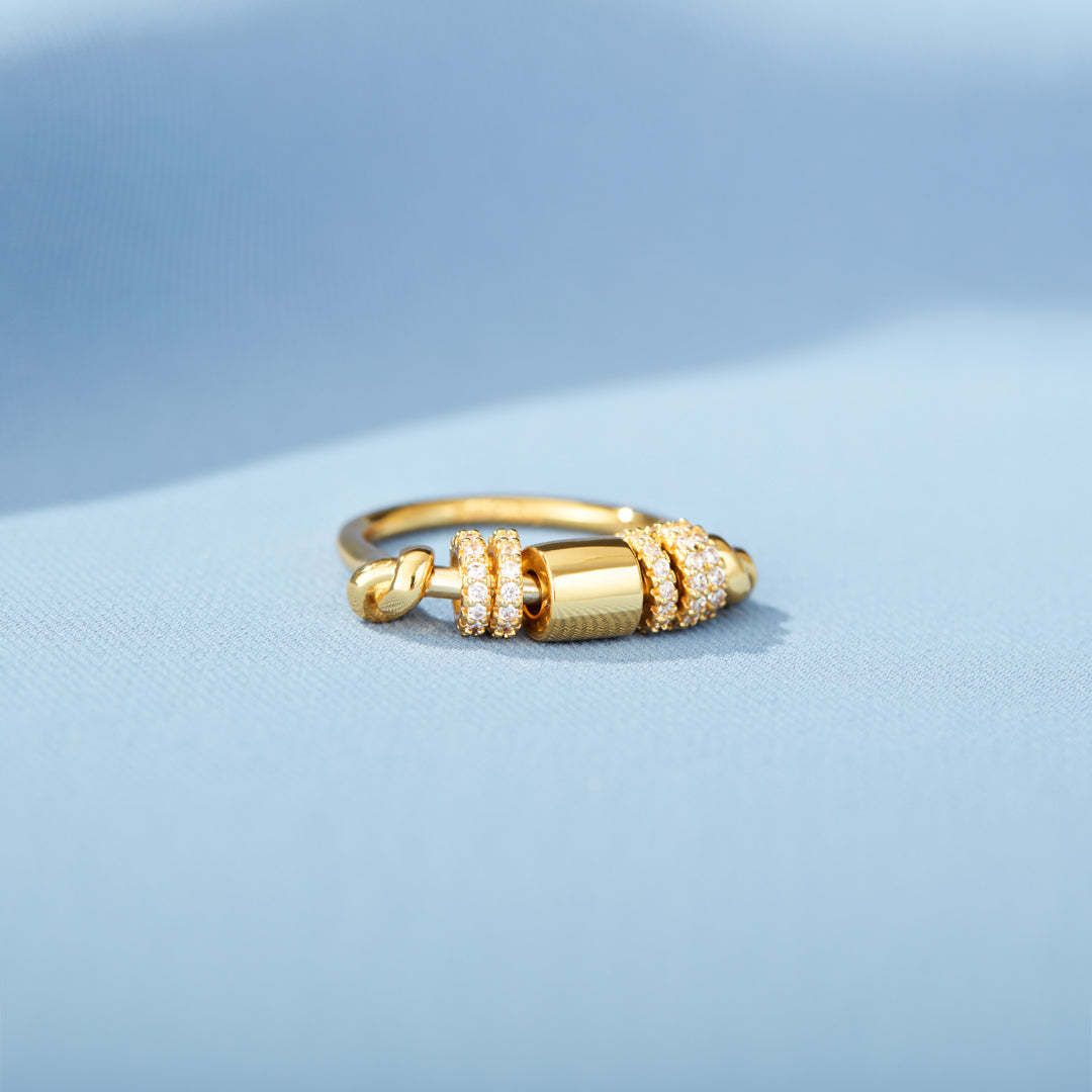 Gold ring with intricate design on a light blue background