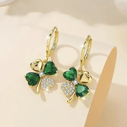 Gold earrings with green gemstones on a beige background